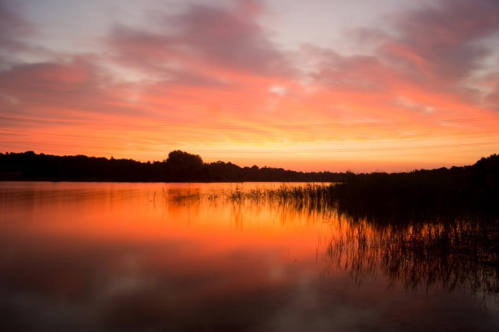 Free Image of Sunset Over Water With Trees in Background 
