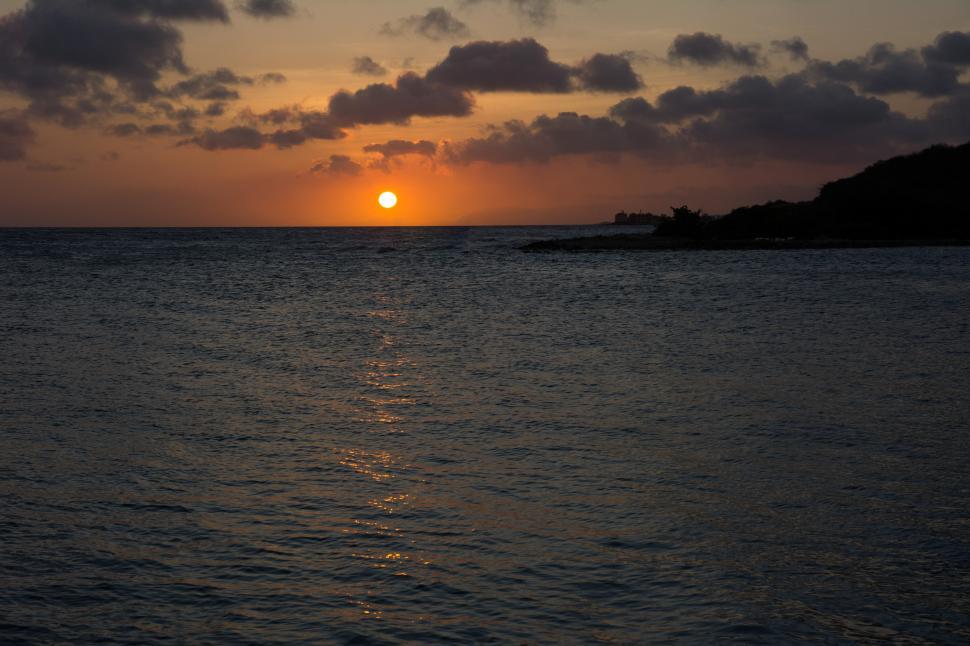Free Image of Sun Setting Over Ocean on Cloudy Day 