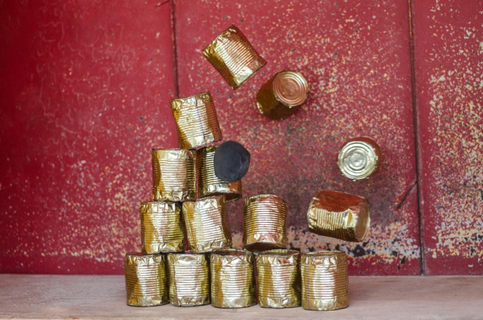 Free Image of Stack of Gold Cans Beside Red Door 