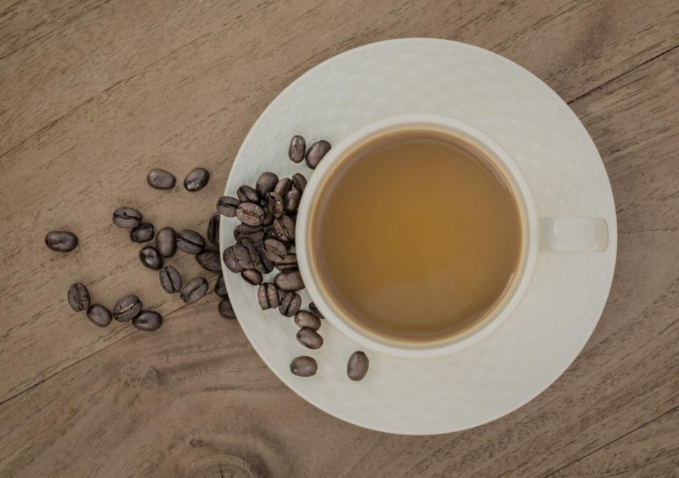Free Image of A Cup of Coffee and Beans on a Wooden Table 