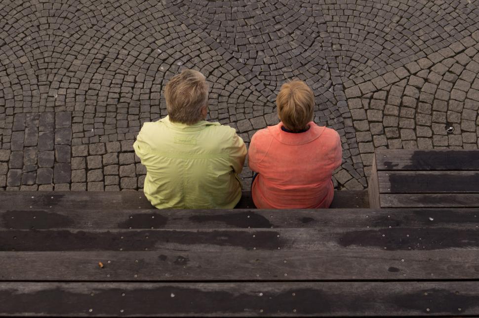 Free Image of Two People Sitting on a Bench Looking at Something 