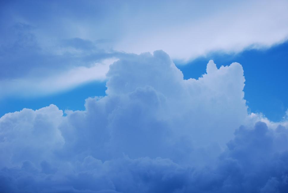 Free Image of Plane Flying Through Cloudy Blue Sky 