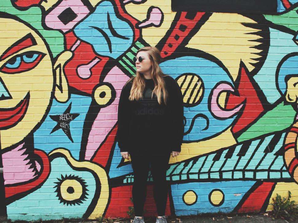 Free Image of Woman Standing in Front of Colorful Wall 