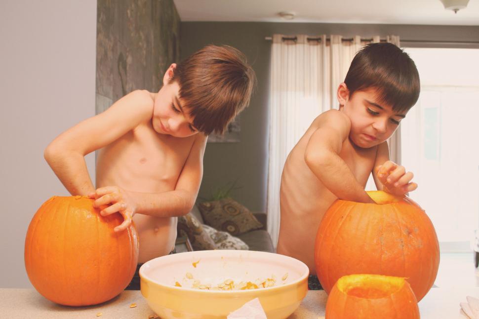 Free Image of Two Young Boys Carving Pumpkins in the Kitchen 