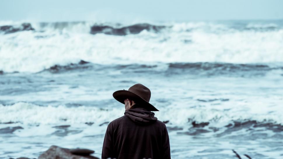Free Image of Man Standing on Beach Next to Ocean 