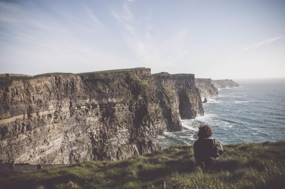 Free Image of Person Sitting on Cliff Overlooking Ocean 