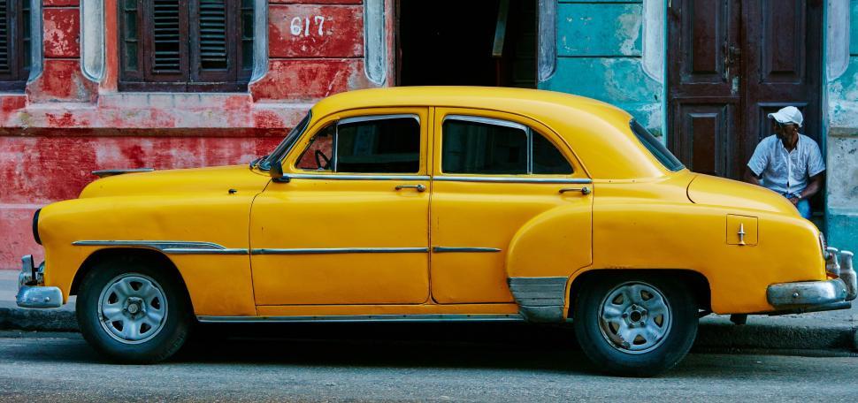 Free Image of Old Yellow Car Parked in Front of Building 