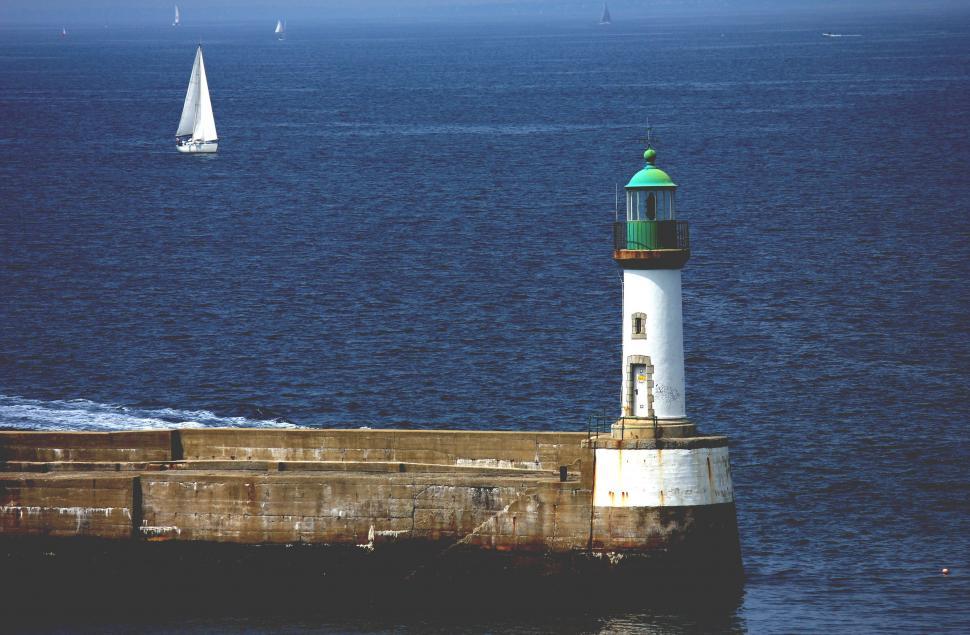 Free Image of Lighthouse and Sailboat in the Background 