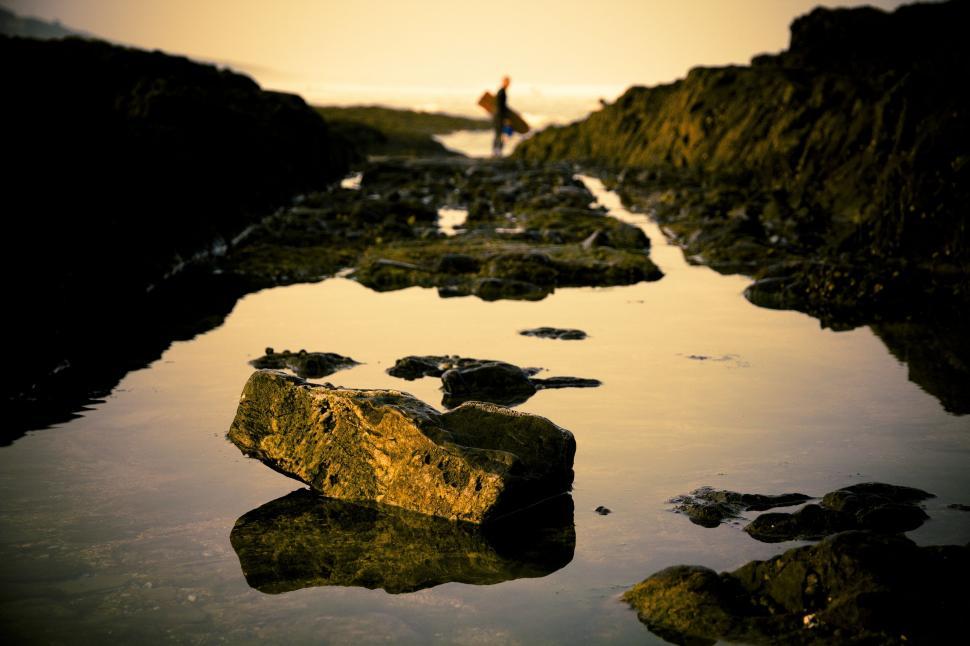 Free Image of Person Standing on Rocky Beach by Water 