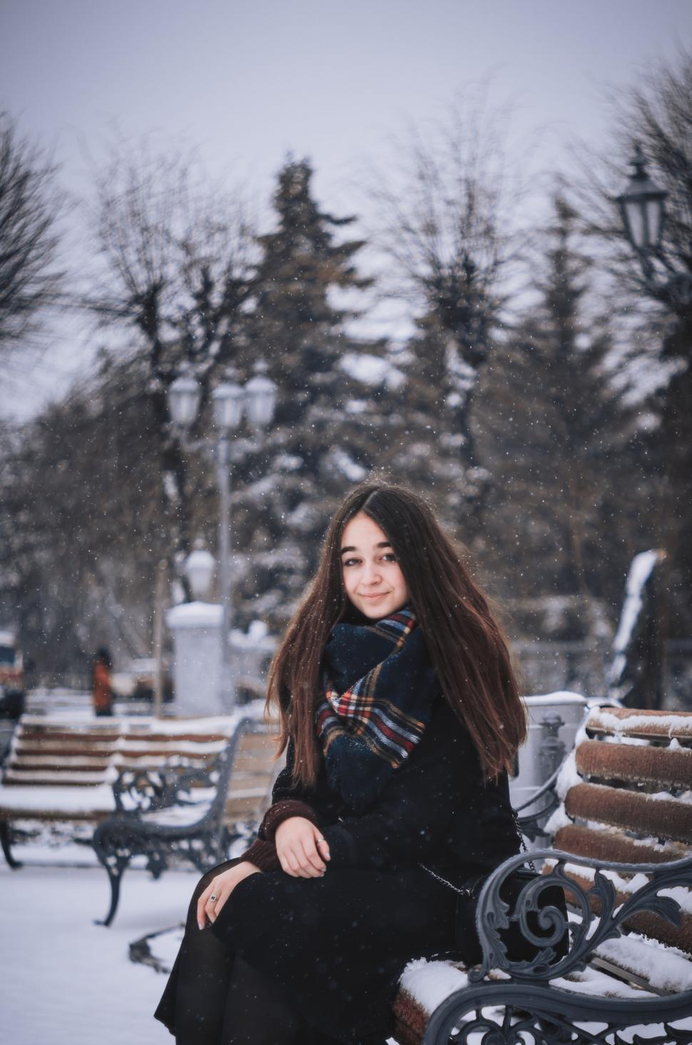 Free Image of Woman Sitting on Bench in Snow 