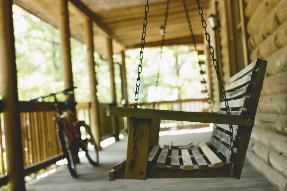 Free Image of Wooden Porch Swing With Bicycle in Background 