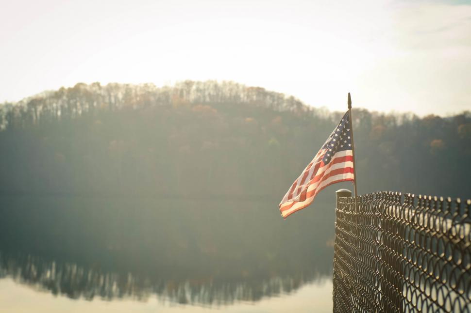 Free Image of American Flag on Fence Overlooking Lake 