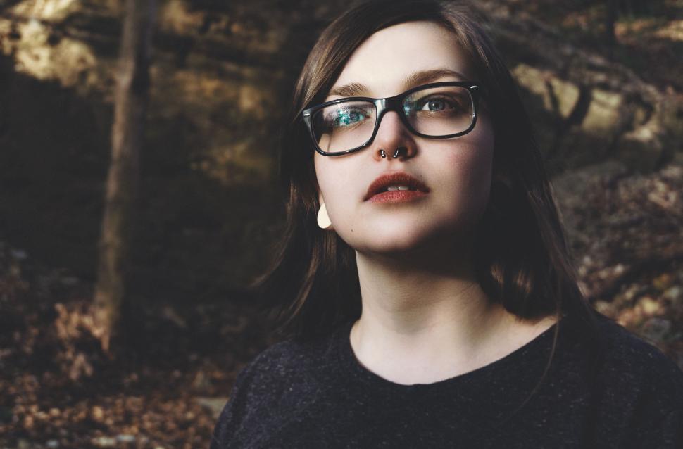 Free Image of Woman in Glasses Standing in Front of Forest 