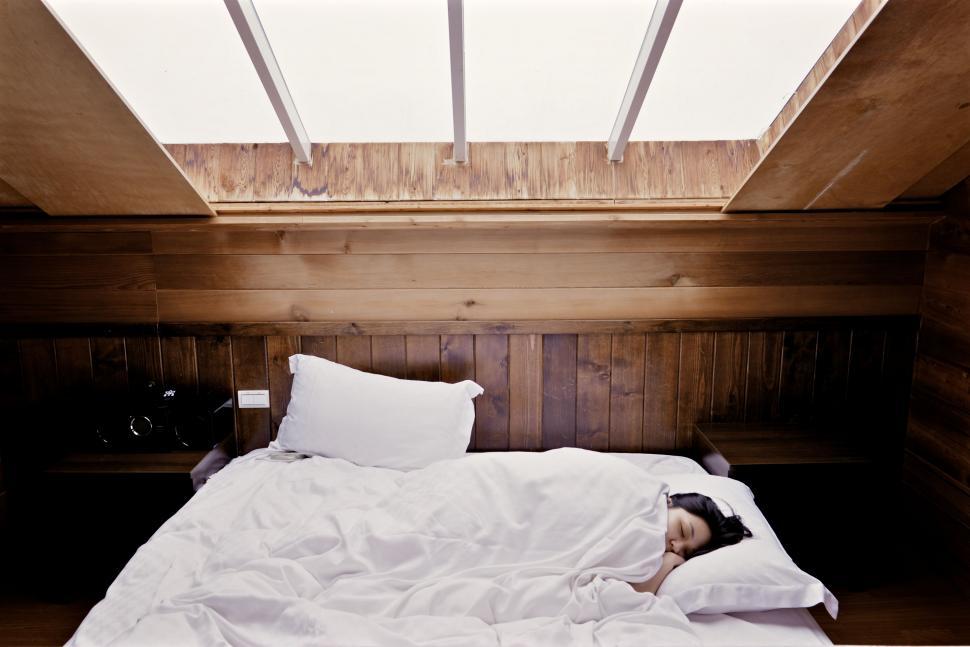 Free Image of Person Laying in Bed Under Skylight 