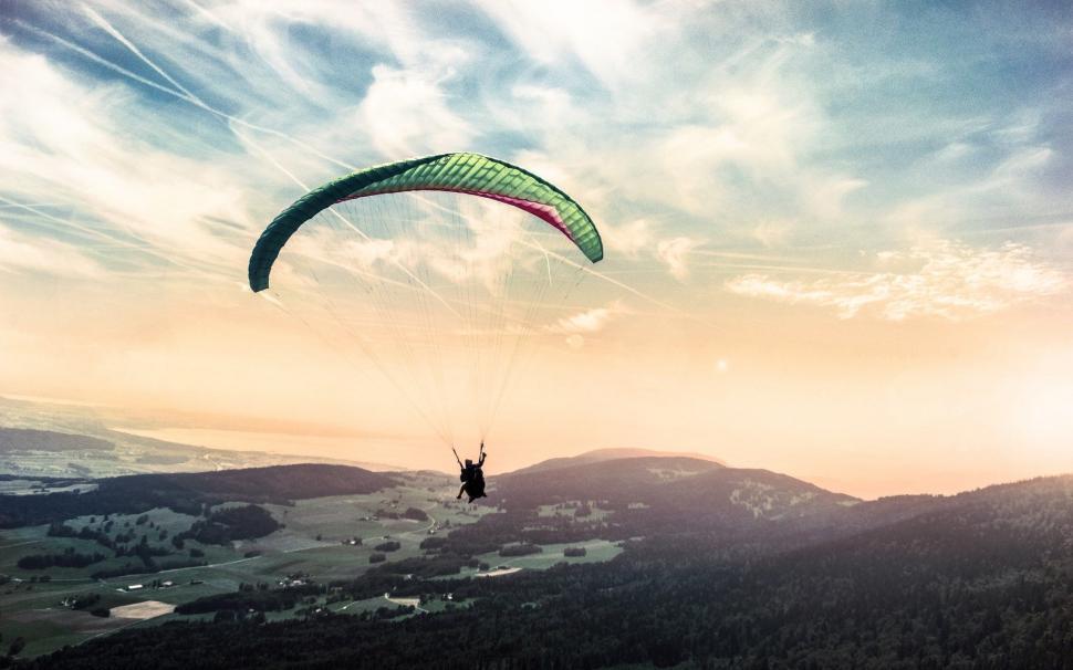 Free Image of Person Paragliding Over Mountain at Sunset 