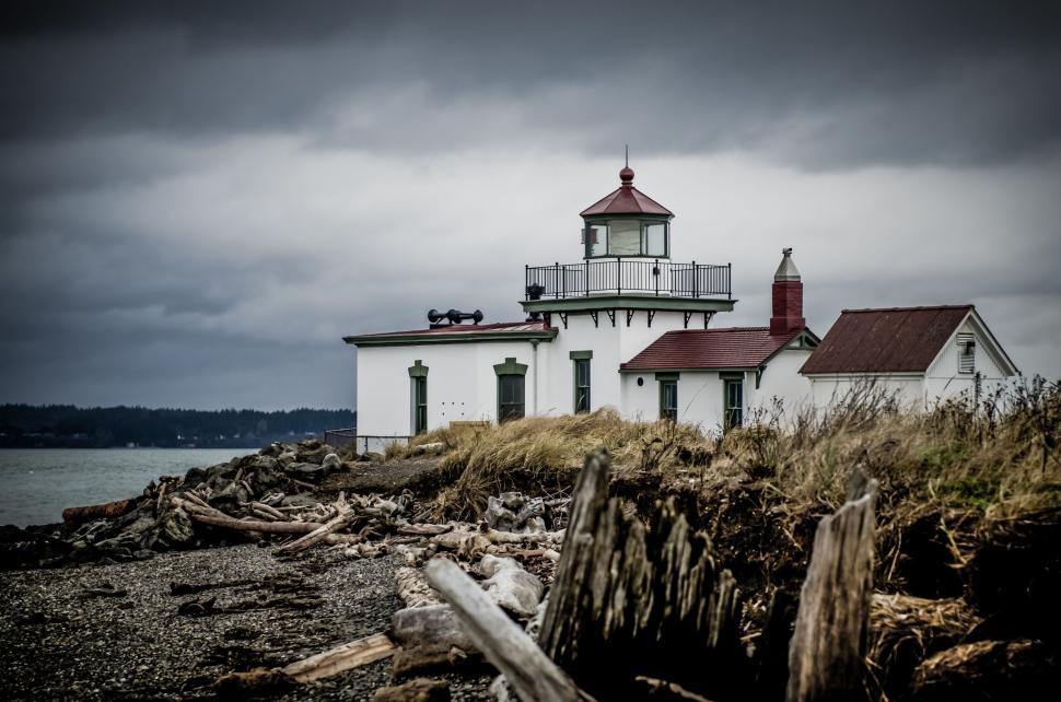 Free Image of Lighthouse on Rocky Shore Under Cloudy Sky 