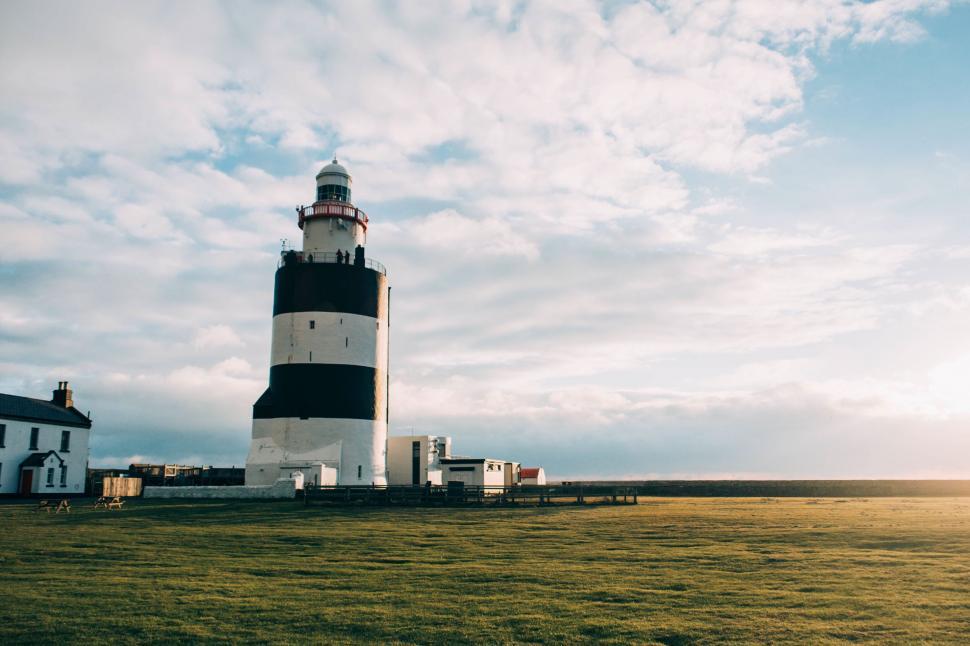 Free Image of Majestic White and Black Lighthouse Overlooking Lush Green Field 