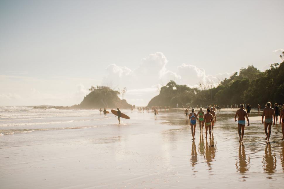 Free Image of Group of People Walking Along Beach Next to Ocean 