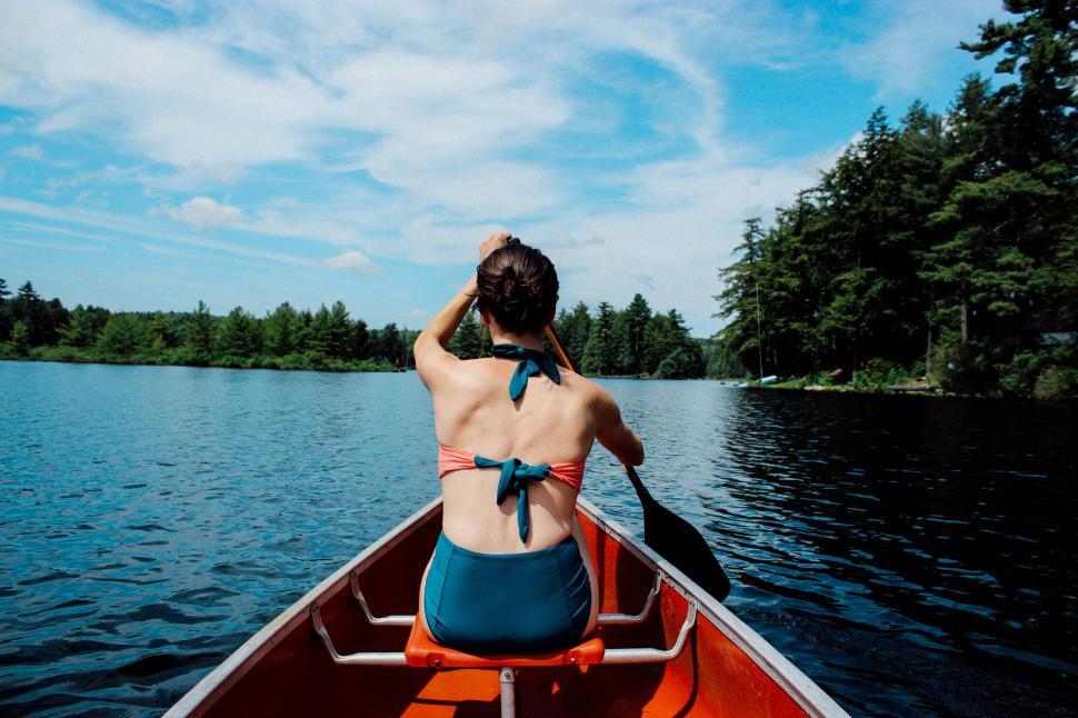 Free Image of Woman in Bikini Paddling Canoe on Lake 