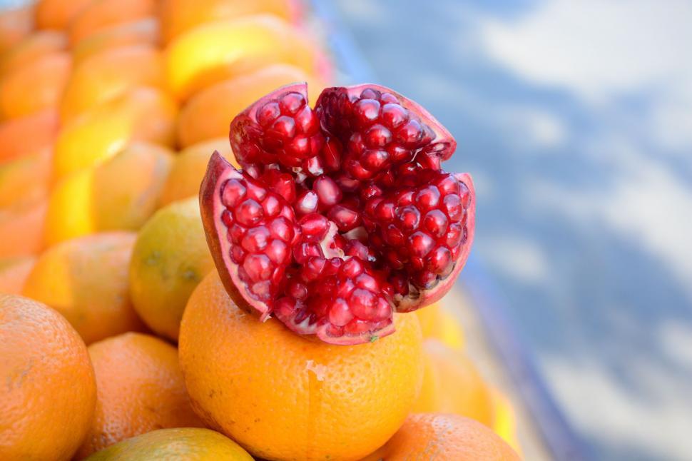 Free Image of Pomegranate Atop Pile of Oranges 