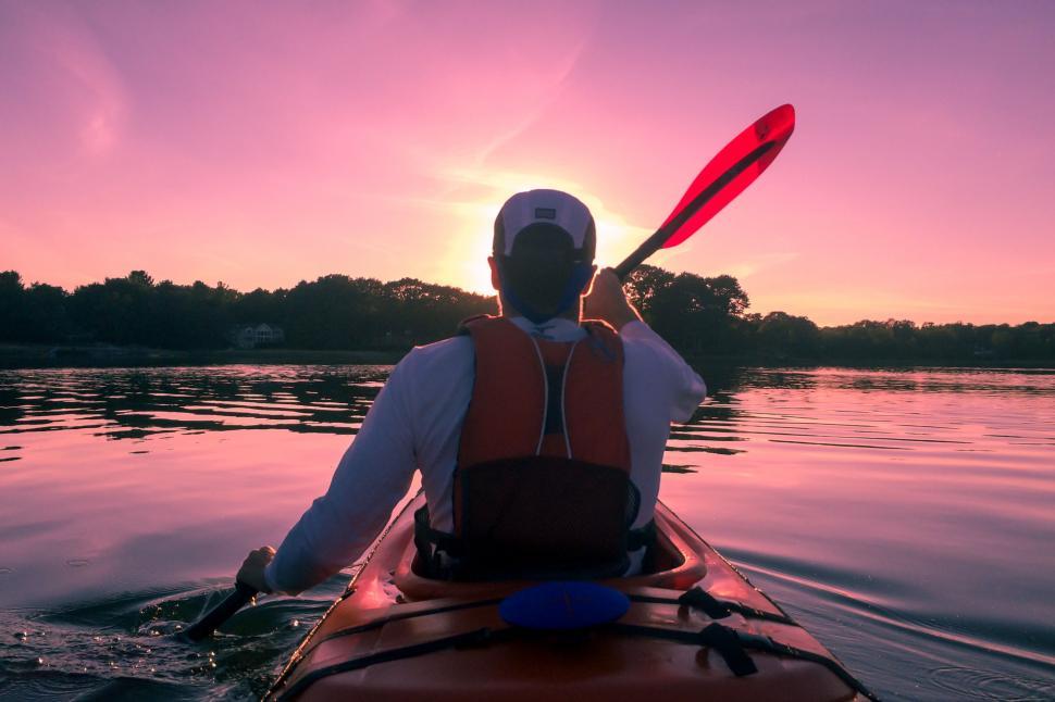 Free Image of Man in Kayak Paddles Through Water at Sunset 