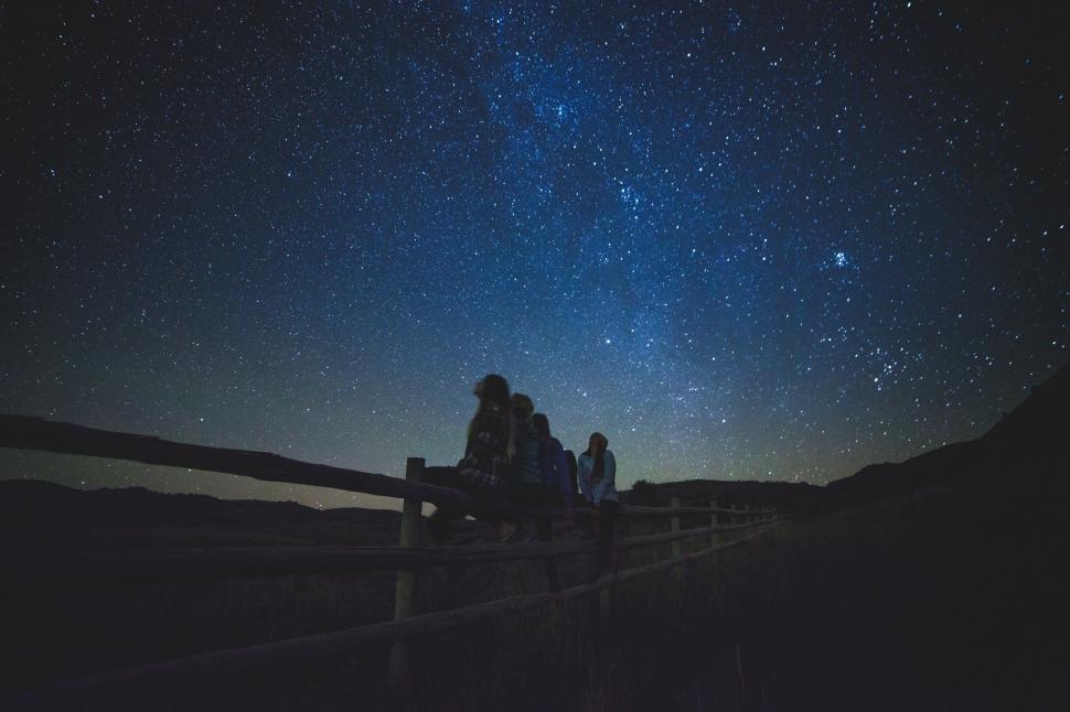 Free Image of Group of People Sitting on a Bench Under Night Sky 