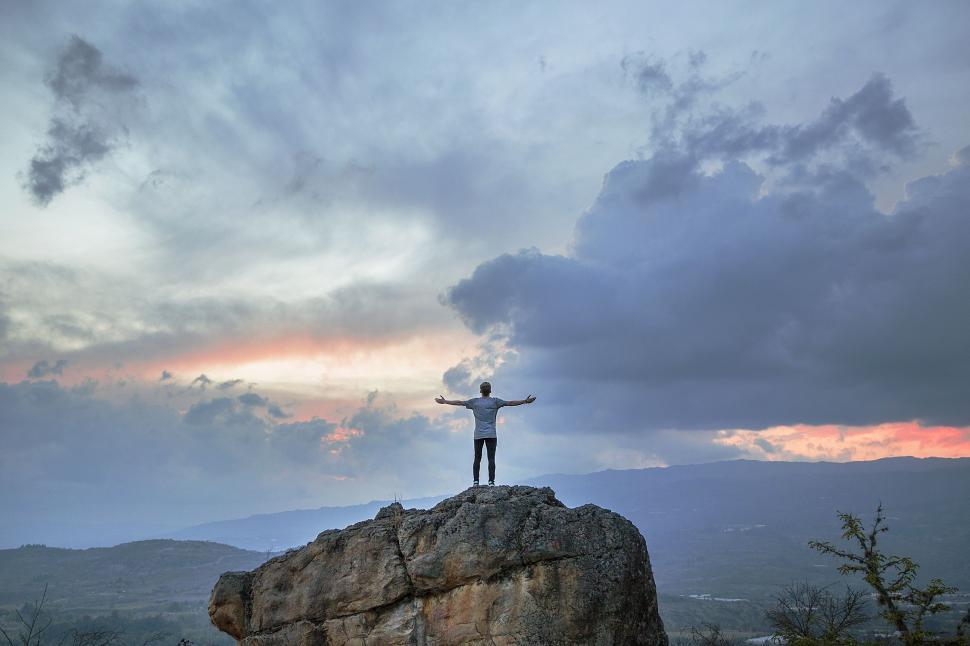 Free Image of Person Standing on Top of Large Rock 