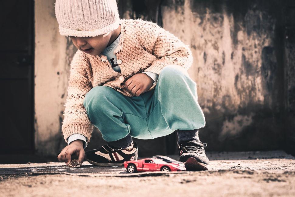 Free Image of Young Boy Playing With Toy Car on Ground 