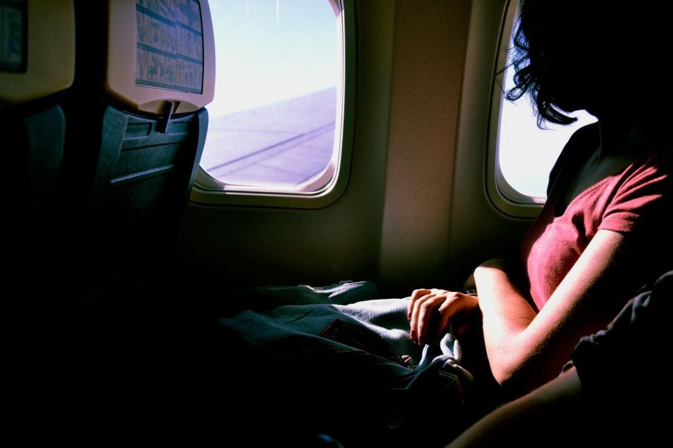 Free Image of Woman Sitting on Airplane Seat Looking Out Window 