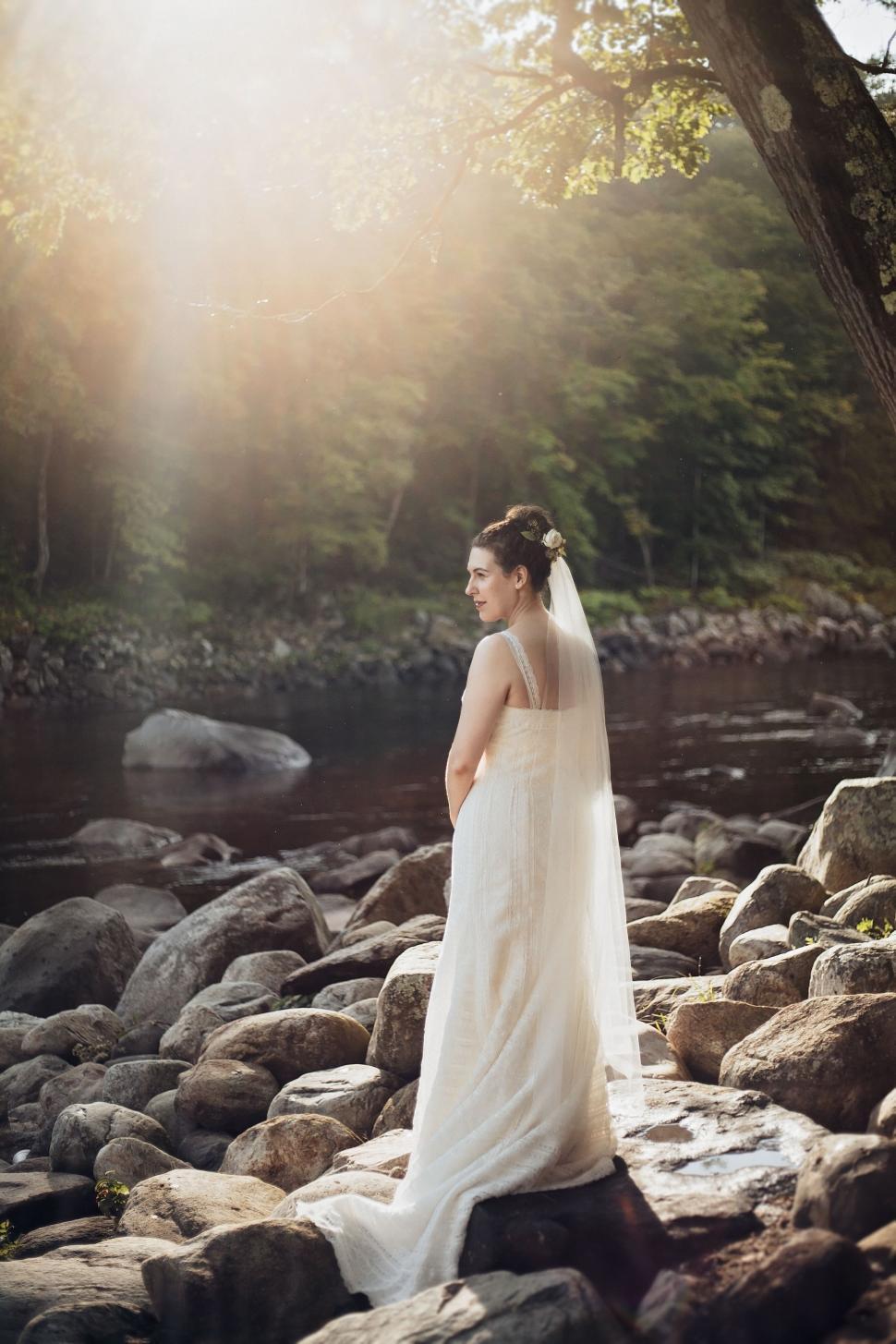 Free Image of Woman in Wedding Dress Standing on Rocks 