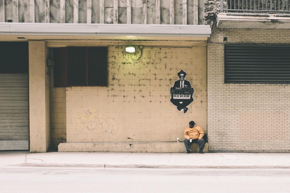 Free Image of Man Sitting on a Bench in Front of a Building 