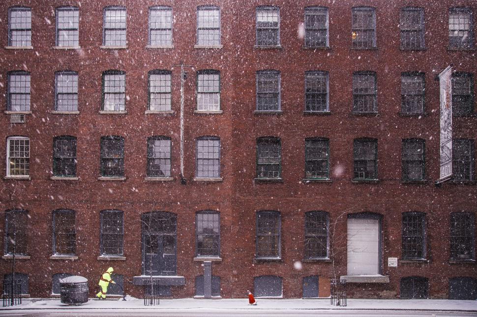 Free Image of Person Walking in Snow in Front of Building 