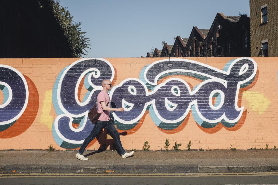 Free Image of Person Walking Past Graffiti Wall 