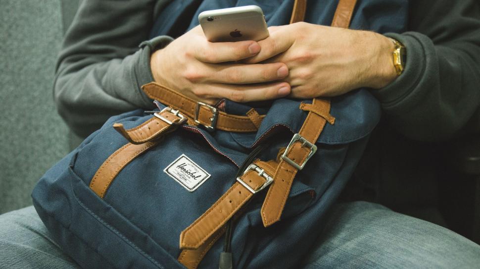 Free Image of Man With Backpack Holding Cell Phone 