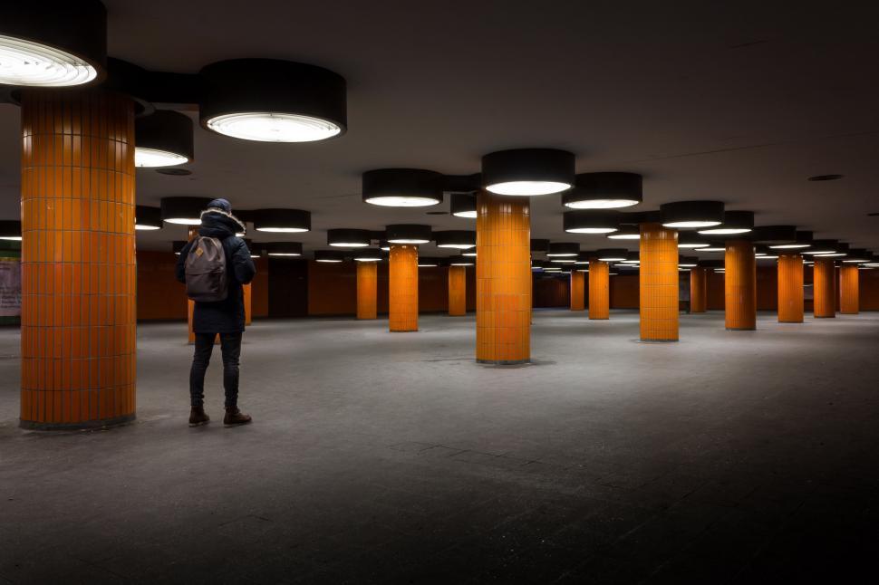 Free Image of Man Standing in Large Room With Orange Columns 