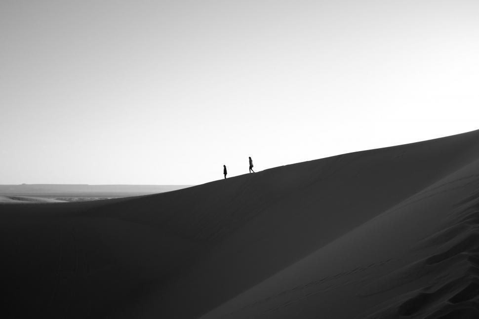 Free Image of Two People Standing on Top of a Sand Dune 