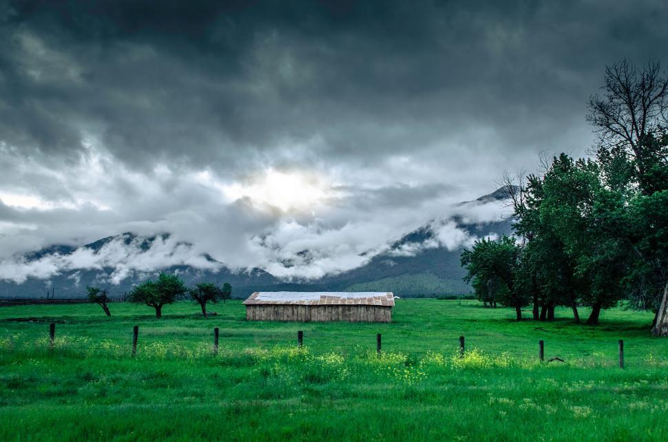 Free Image of Green Field With Barn and Mountains in Background 