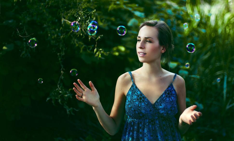 Free Image of Woman in Blue Dress Blowing Bubbles 