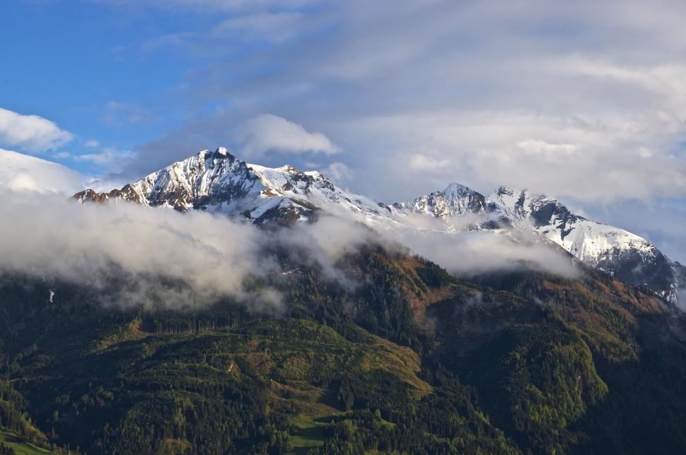 Free Image of Majestic Mountain Blanketed in Snow and Clouds Under Sunny Sky 