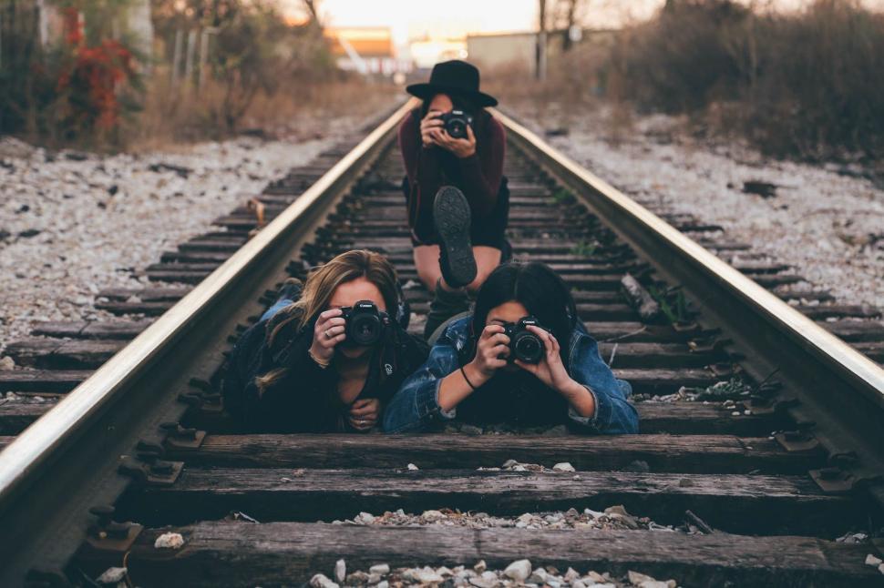 Free Image of Two Women Taking Pictures on a Train Track 