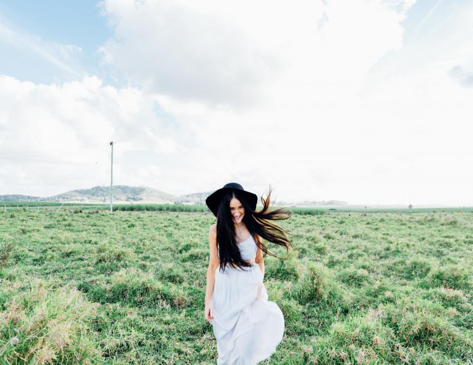 Free Image of Woman in White Dress and Hat Walking Through a Field 
