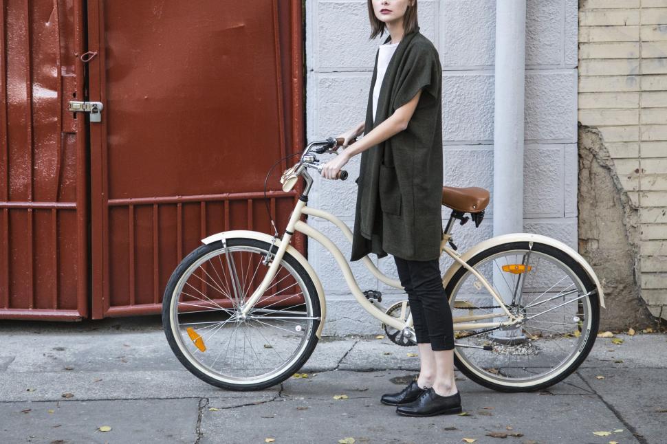 Free Image of Woman Standing Next to Bike on Sidewalk 