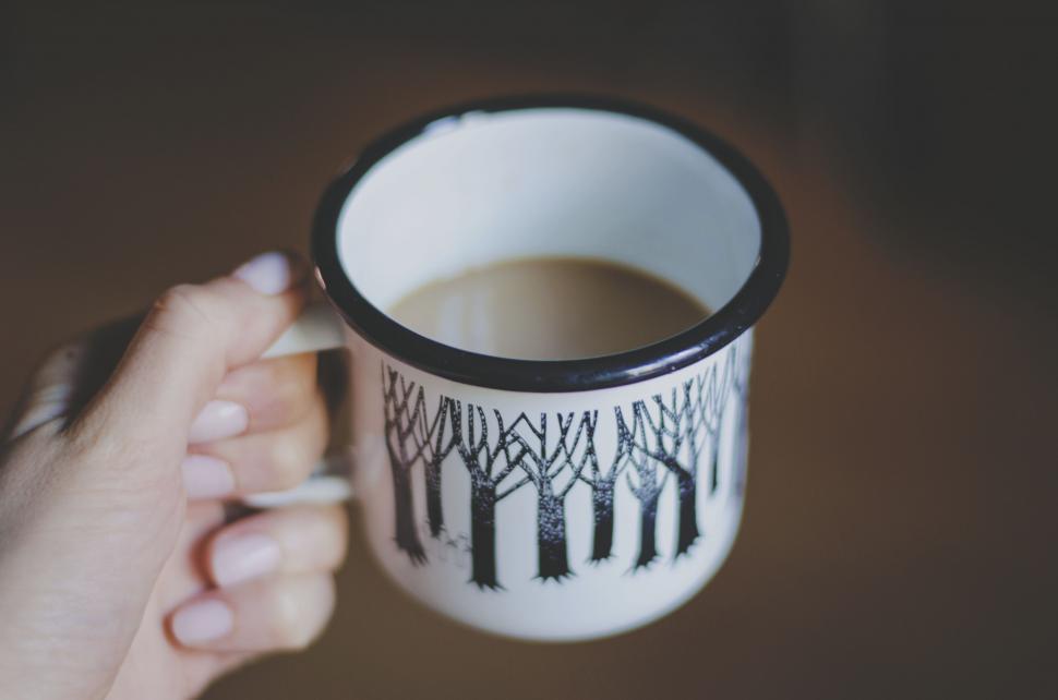 Free Image of Hand Holding Coffee Cup With Tree Design 
