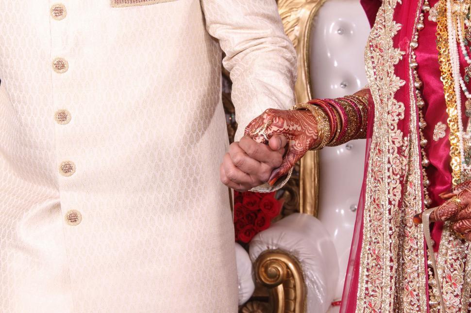 Free Image of Bride and Groom Holding Hands in Front of a Chair 