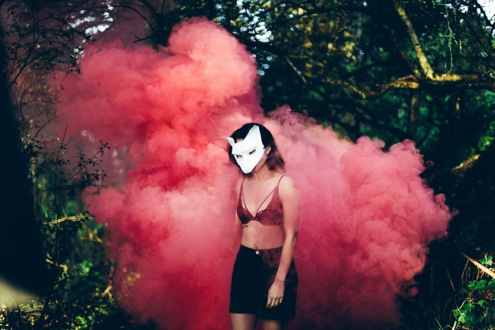Free Image of Woman Wearing Mask Standing in Front of Pink Smoke 