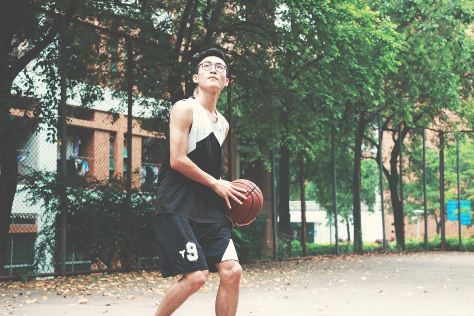 Free Image of Young Man Holding Basketball on Basketball Court 