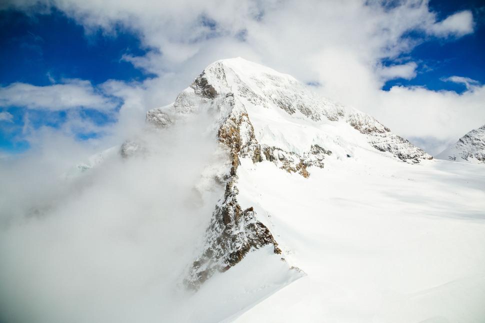 Free Image of Snow-Covered Mountain Beneath Cloudy Blue Sky 