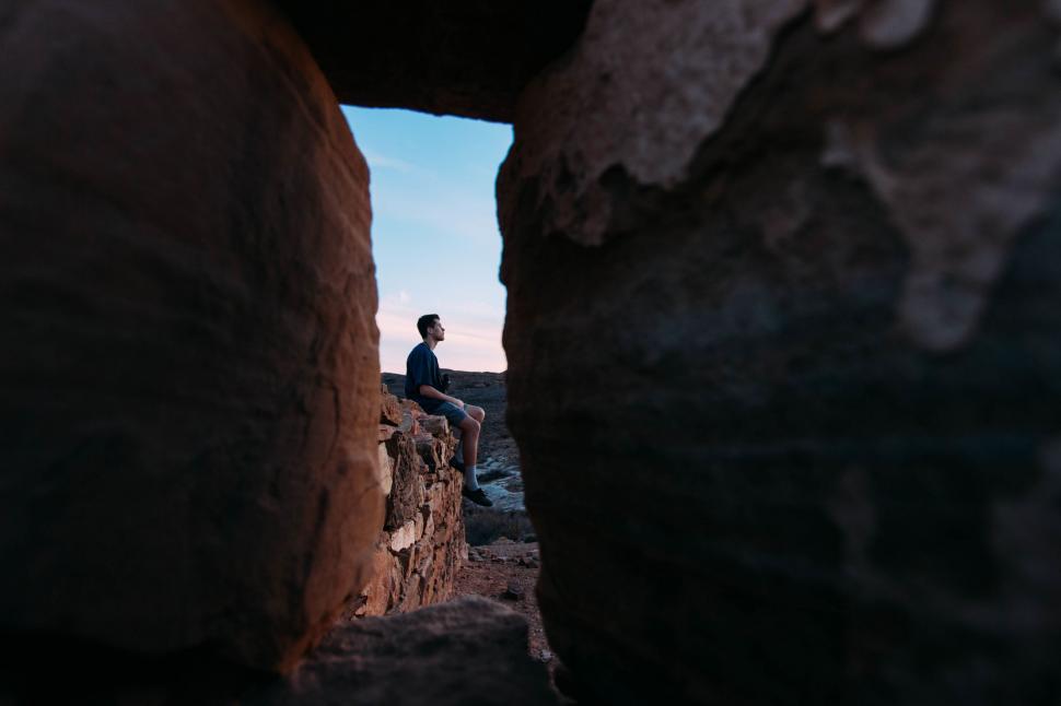 Free Image of Man Sitting on Rock, Looking Into the Distance 
