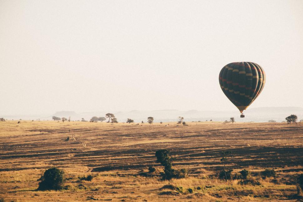 Free Image of Hot Air Balloon Flying Over Dry Grass Field 