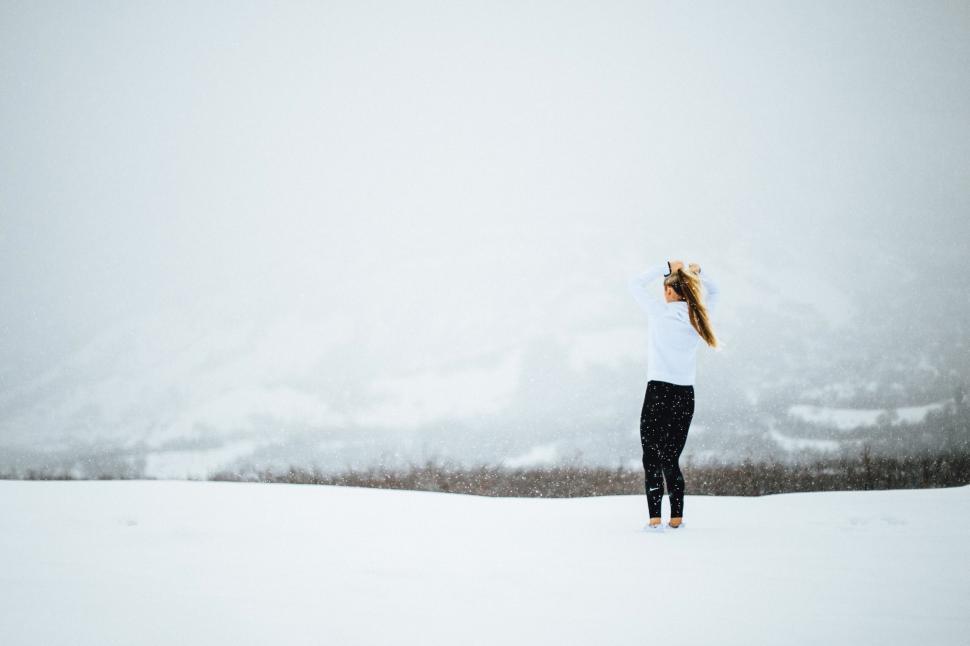 Free Image of Woman Standing in Snow With Hair in Wind 